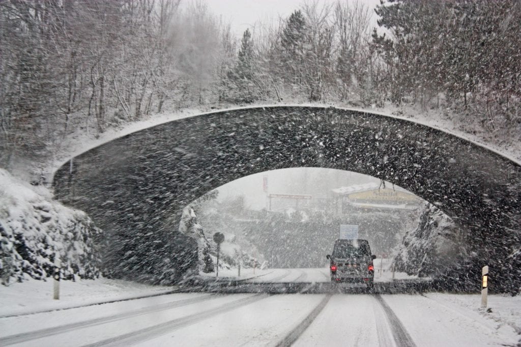van driving under a bridge in a snowy blizzard